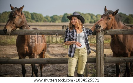 American woman on a horse farm. Portrait of girl in cowboy hat with a  horses.