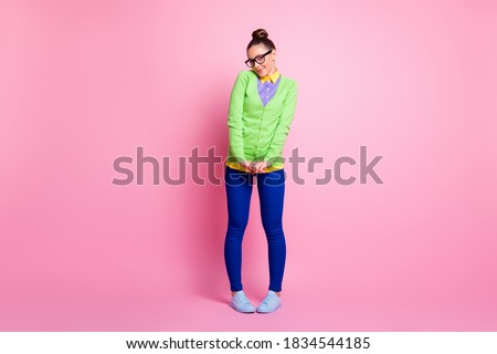Full body size photo of lovely shy young girl knot hairstyle hold hands smiling blushing want ask guy phone number clumsy legs wear spectacles colored clothes bright pink color background