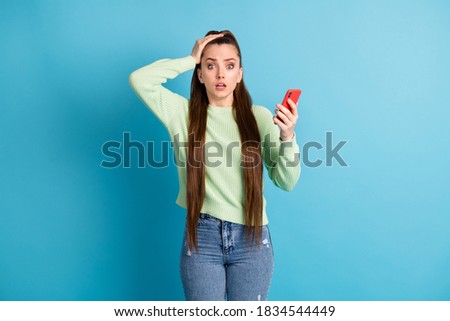 Photo portrait of unhappy girl holding head phone with one hand isolated on pastel blue colored background
