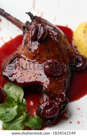 Grilled duck leg with polenta and sauce. Roasted duck leg on white plate on table