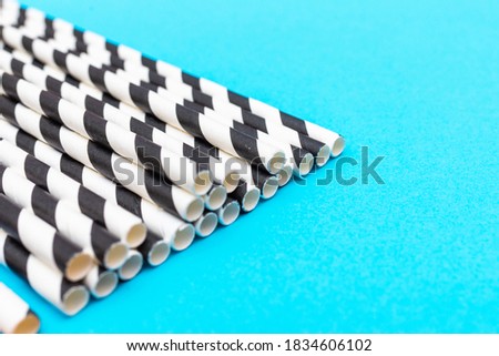 A lot of cocktail striped black and white tubes. Pattern background flat lay blue background copy space.