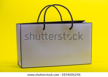 White paper bag on yellow background. Concept of shopping.