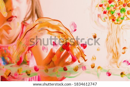 Beautiful young girl painting image on the glass with colorful finger. Selective focus.
