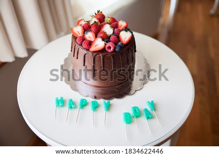 chocolate birthday cake with red berries and  happy bday candles