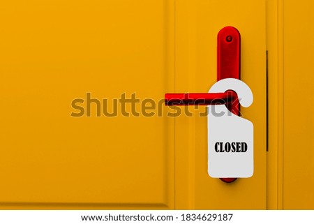 Closed door with a closed sign. Yellow door of a hotel, restaurant or bar with a red handle and a paper label with a warning.