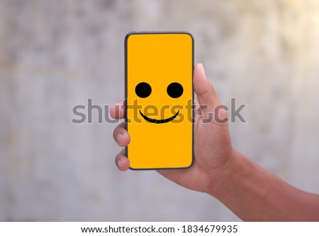 A man with a cell phone, The phone screen shows a smiley picture.