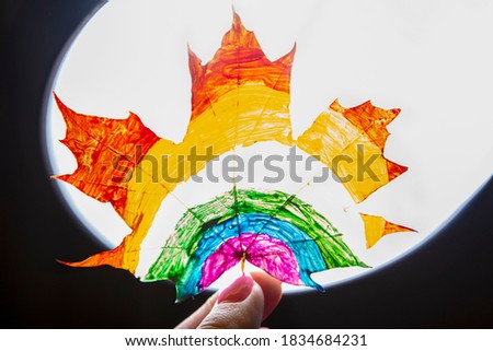 Over lightened leaf of maple with rainbow pattern drawn on it - rays of light are coming through