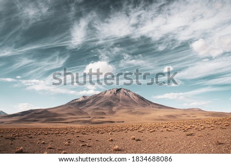 Mountain with light brown grass under cloudy blue sky