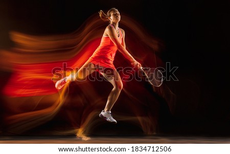 Competition. Professional female tennis player training isolated on black studio background in mixed light. Woman in sportsuit practicing. Healthy lifestyle, sport, workout, motion and action concept.