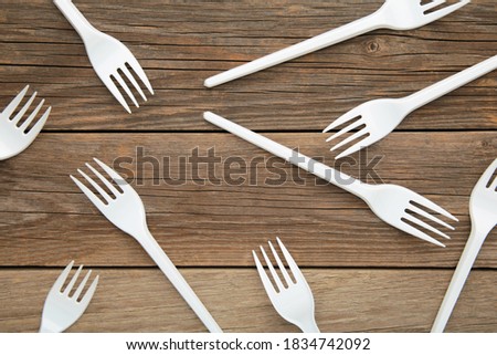 Many white plastic forks on a grey wooden background. Top view.
