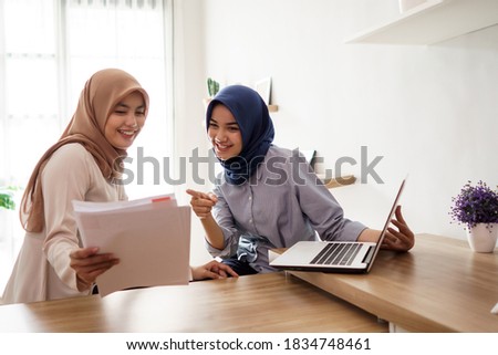portrait of beautiful muslim women smile while explaining project on paper to her partner at office studio
