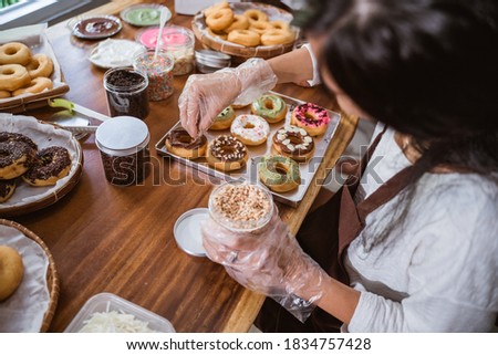 Chef sprinkled donuts with nuts and decorated donuts on the table in the kitchen Royalty-Free Stock Photo #1834757428