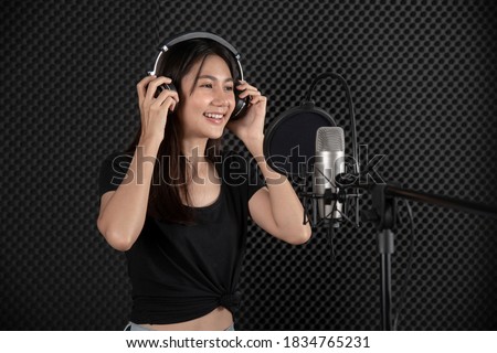 asian  lady singing with smile   in music studio recording room