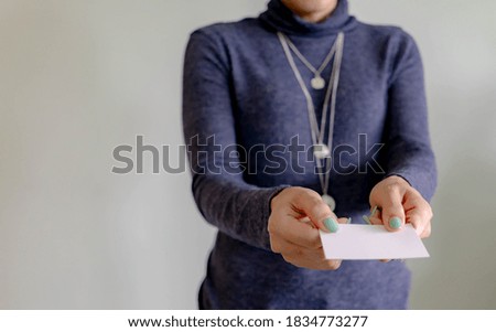 Asian businesswomans hand holding a blank business card. Chinese woman professional holding a blank white business card