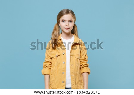 Pretty little blonde kid girl 12-13 years old in yellow jacket posing isolated on pastel blue wall background children studio portrait. Childhood lifestyle concept. Mock up copy space. Looking camera Royalty-Free Stock Photo #1834828171