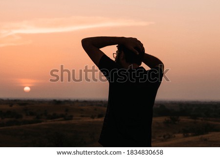 Silhouette of an Indian man standing in front of the sun during the sunset