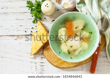 Healthy food concept. Diet turkey soup with vegetables served croutons on a white wooden table. Top view flat lay background. Copy space.