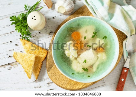 Healthy food concept. Diet turkey soup with vegetables served croutons on a white wooden table. Top view flat lay background. 