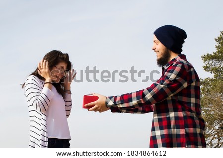 boyfriend gives his girlfriend a gift in a red box on the street