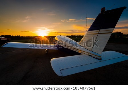 Quadruple aircraft parked at a private airfield. Rear view of a plane with a propeller on a sunset background. Royalty-Free Stock Photo #1834879561