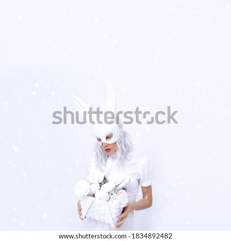 Fashion Magic Rabbit Girl in white space holds winter Christmas decor box. Minimal fashion festive Christmas / New Year holidays party celebration concept.