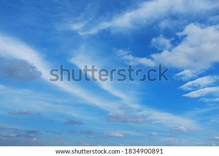 White cirrus clouds on a background of dark blue sky. The cloud resembles a flying angel.