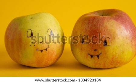 Painted faces on apples on a yellow background. Apple Jack as an alternative to Halloween Jack. Children fun