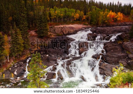 Early fall colours provide contrast to the stark rock framing Cameron falls along the Ingraham Trail in Canada's Northwest Territories Royalty-Free Stock Photo #1834925446