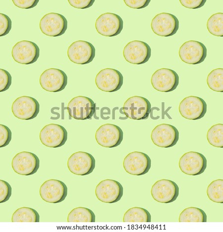 Zucchini isolated on a green background. Seamless pattern of zucchini on a mint background. Flat layout of sliced zucchini slices. Creative composition on the theme of dietary nutrition. Top view.