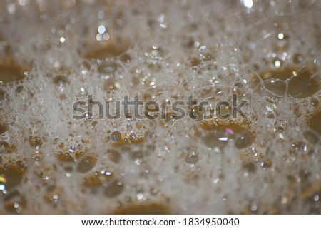 Closeup selective view of Foam and soap bubbles over water. white foam on water with brownish background