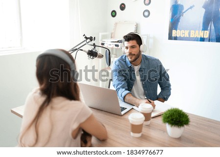 Portrait of a male blogger making questions to his guest and taking some notes during an interview in his podcast