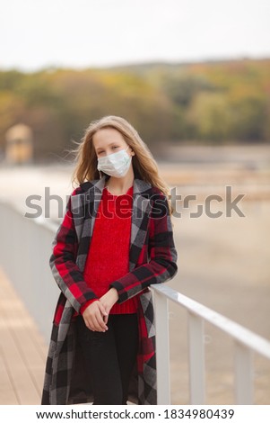 Cute girl in a mask on a walk in the fall