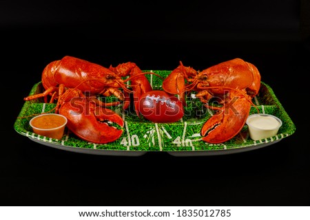 Restaurant food for american football game partry. Red lobsters on green plate with ball.