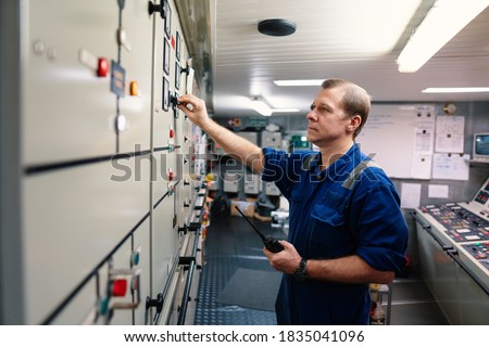 Marine engineer officer controlling vessel engines and propulsion in engine control room ECR. Ship maintenance Start or stop of main engine Royalty-Free Stock Photo #1835041096