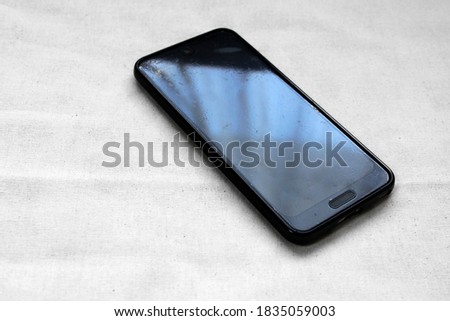 A window reflected on the screen of a scratched smartphone
