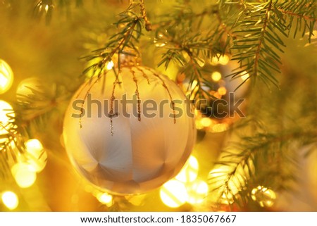 Christmas and New Year background.Golden ball and glowing shining garlands decoration on the christmas tree.Christmas tree festive decor.Winter holidays symbol.holidays wallpaper