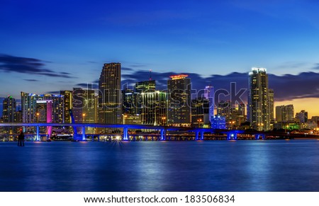 Miami city skyline panorama at dusk with urban skyscrapers over sea with reflection 
