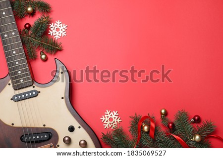Christmas music. Flat lay composition with guitar and fir tree branches on red background, space for text