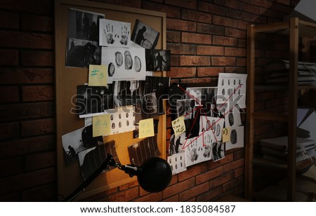 Boards with fingerprints, crime scene photos and red threads on brick wall. Detective agency
