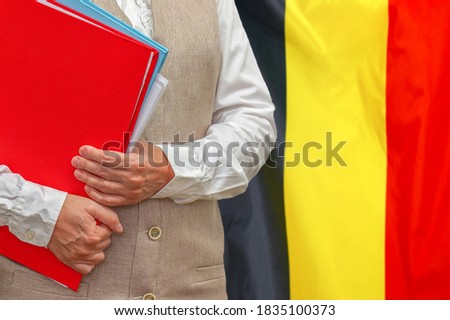 Woman holding red folder on Belgium flag background. Education and jurisprudence concept in Belgium