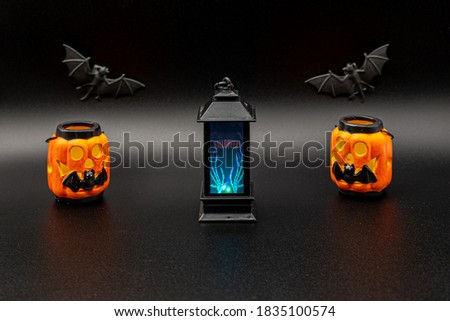 Halloween stuff composition with flying black lantern, lightned pumpkins and bats on the background with copy space.