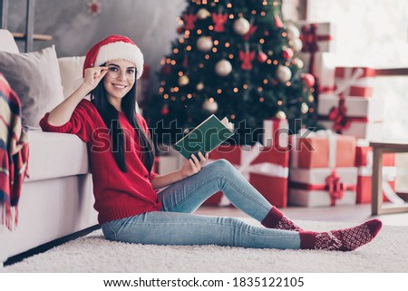 Full body photo of smart girl sir carpet read book wear santa claus hat sweater in house indoors with x-mas christmas tinsels.