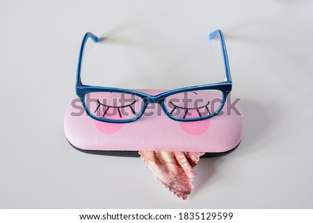 Rectangular glasses in bright blue frames on a funny case for glasses light background close-up