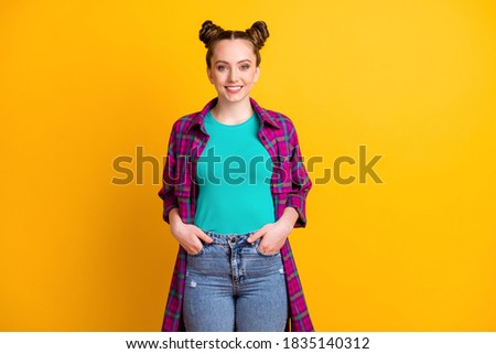Photo of attractive charming teen lady two funny buns hold hands, pockets self-confident person good mood wear casual plaid long magenta shirt jeans isolated yellow bright color background