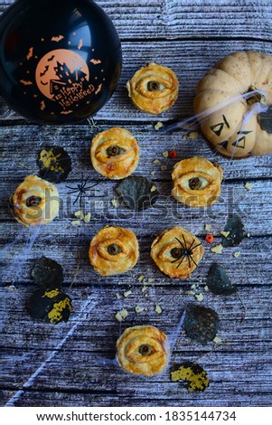 Top view of Halloween autumn decor. Homemade cakes in the shape of eyes and a spider web with spiders on a wooden background. Vertical