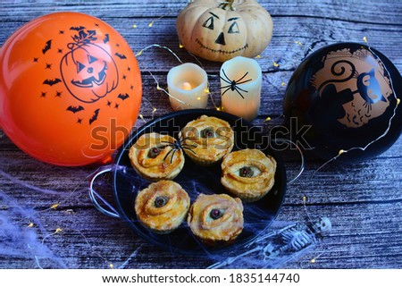 Happy Halloween concept. Funny pastries, painted pumpkins, spiders on spider webs, orange and black balloons on a rustic background. Soft focus