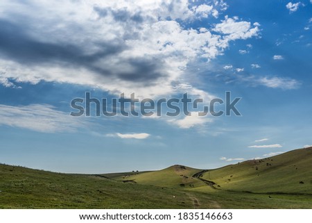 Mountain and grasslands and roads under blue sky and white clouds in Xinjiang, China in summer