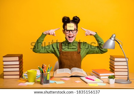 Photo of amazed high school girl sit table do materials home work point index finger sticker paper forehead wear green style stylish, trendy sweater isolated bright shine color background