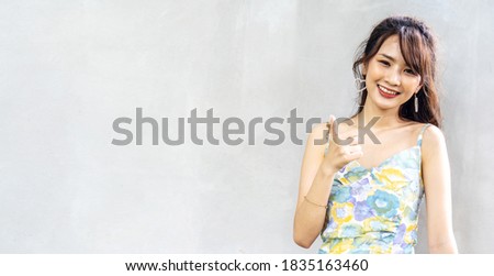 Beautiful young asian woman thumbs up with big smile happy beaming face with positive emotions of content and happiness. standing isolated over gray background