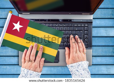 woman hands and flag of Togo on computer, laptop keyboard 